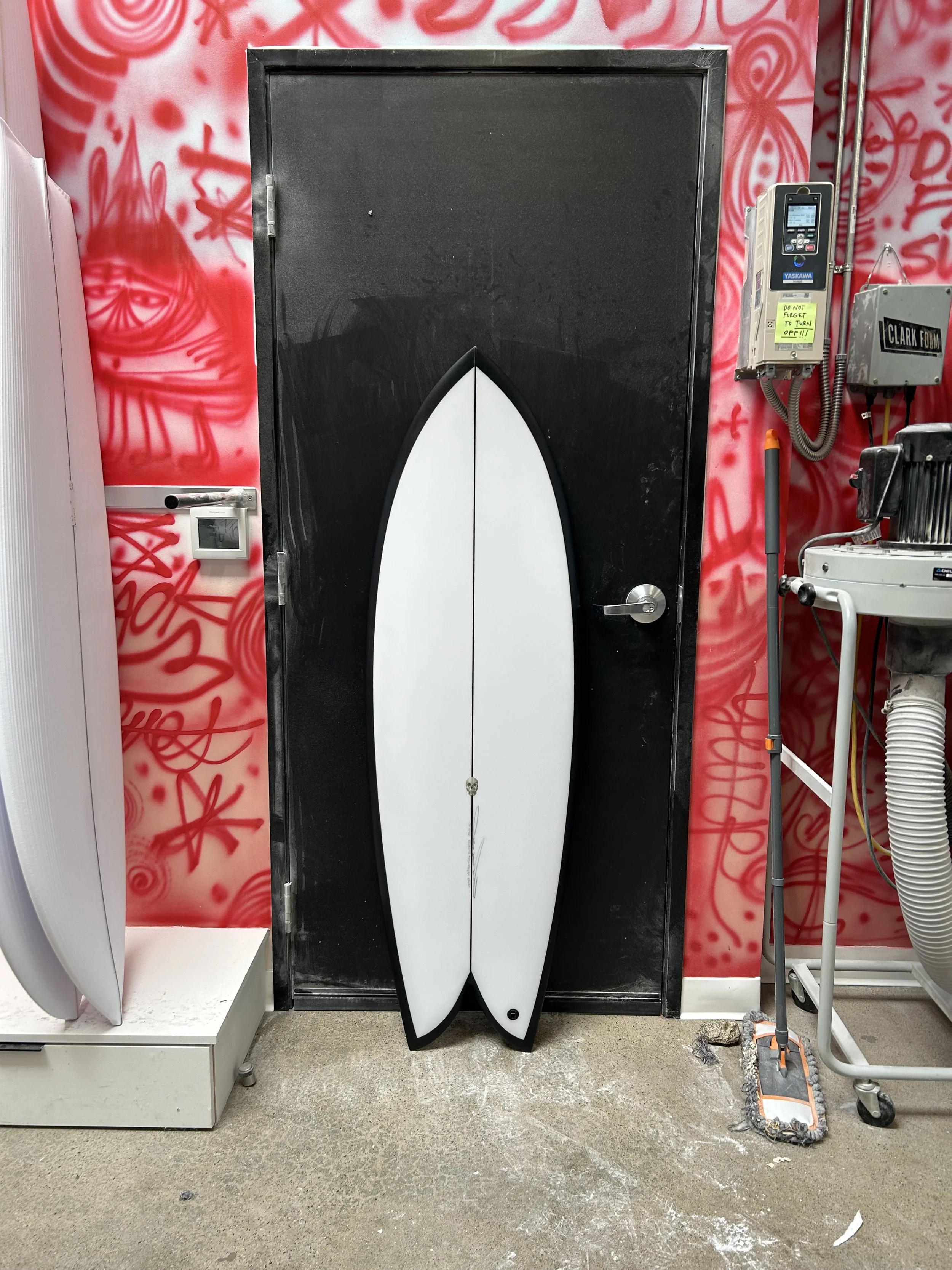 white fish surfboard with black rails against black door