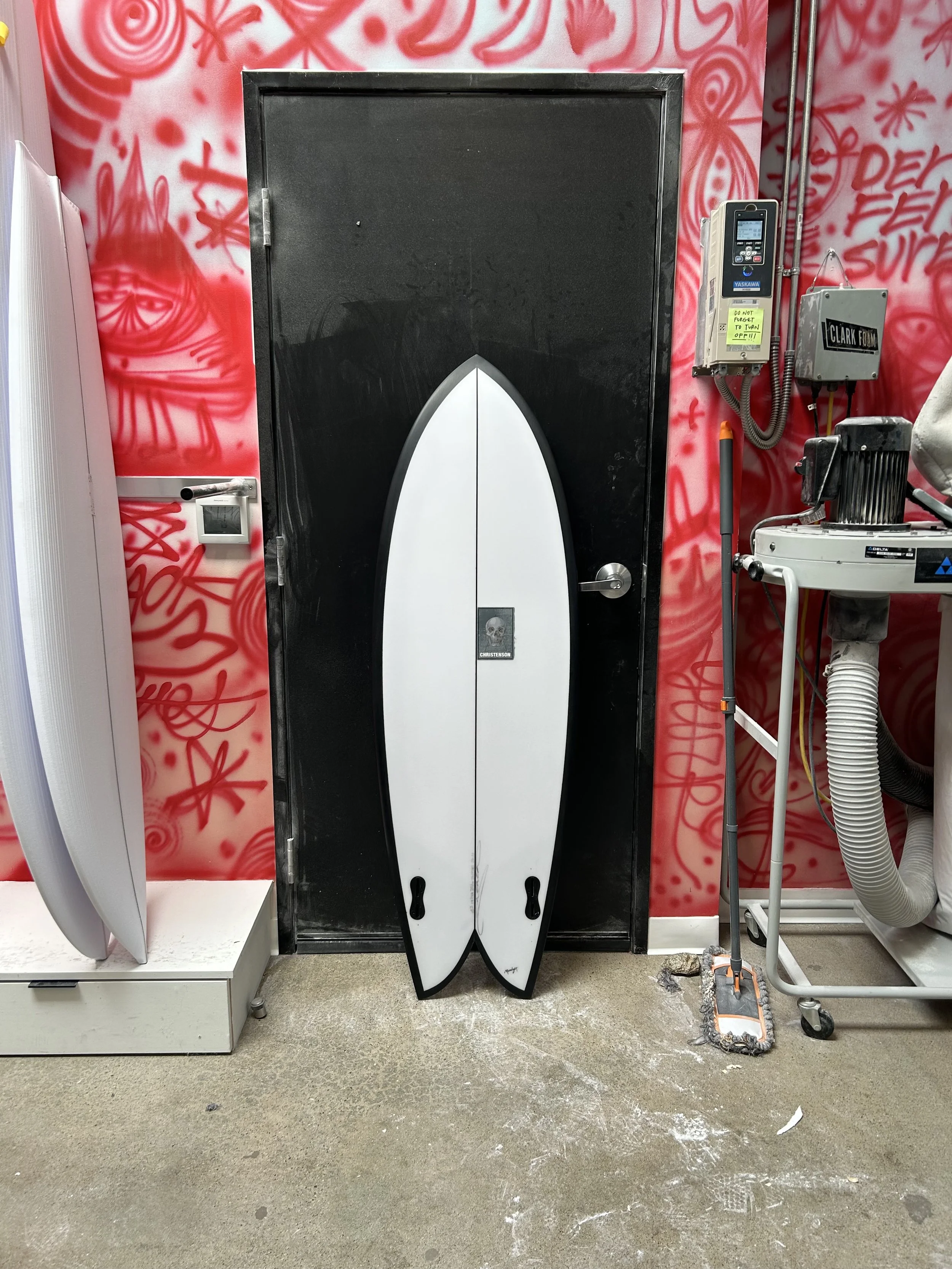 white fish surfboard with black rails against black door
