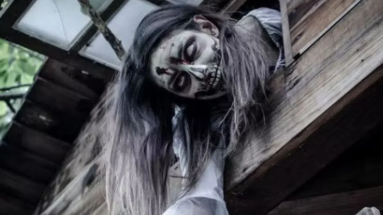 A chilling zombie face pokes out of a haunted house.