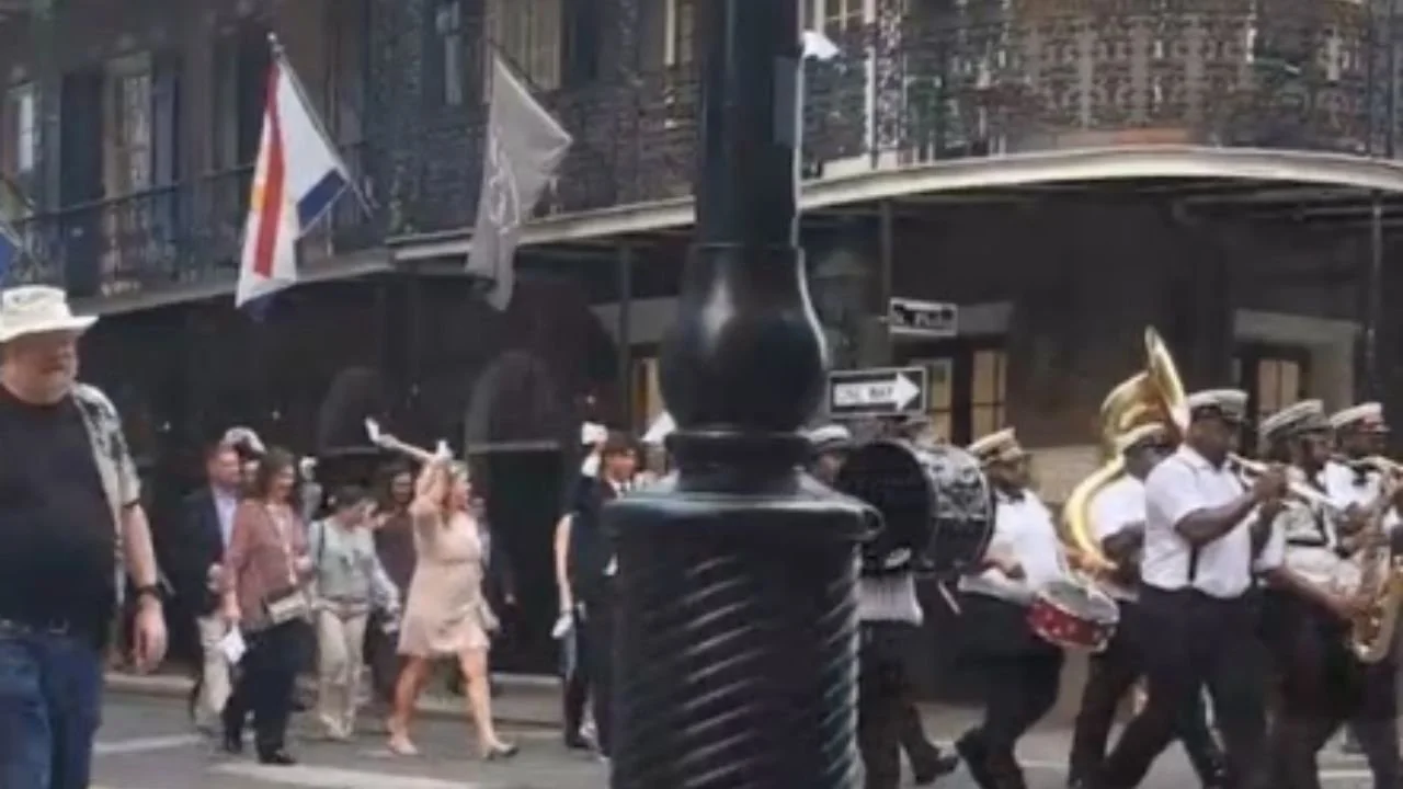 Second Line parade in New Orleans with a brass band marching past French Quarter balconies.