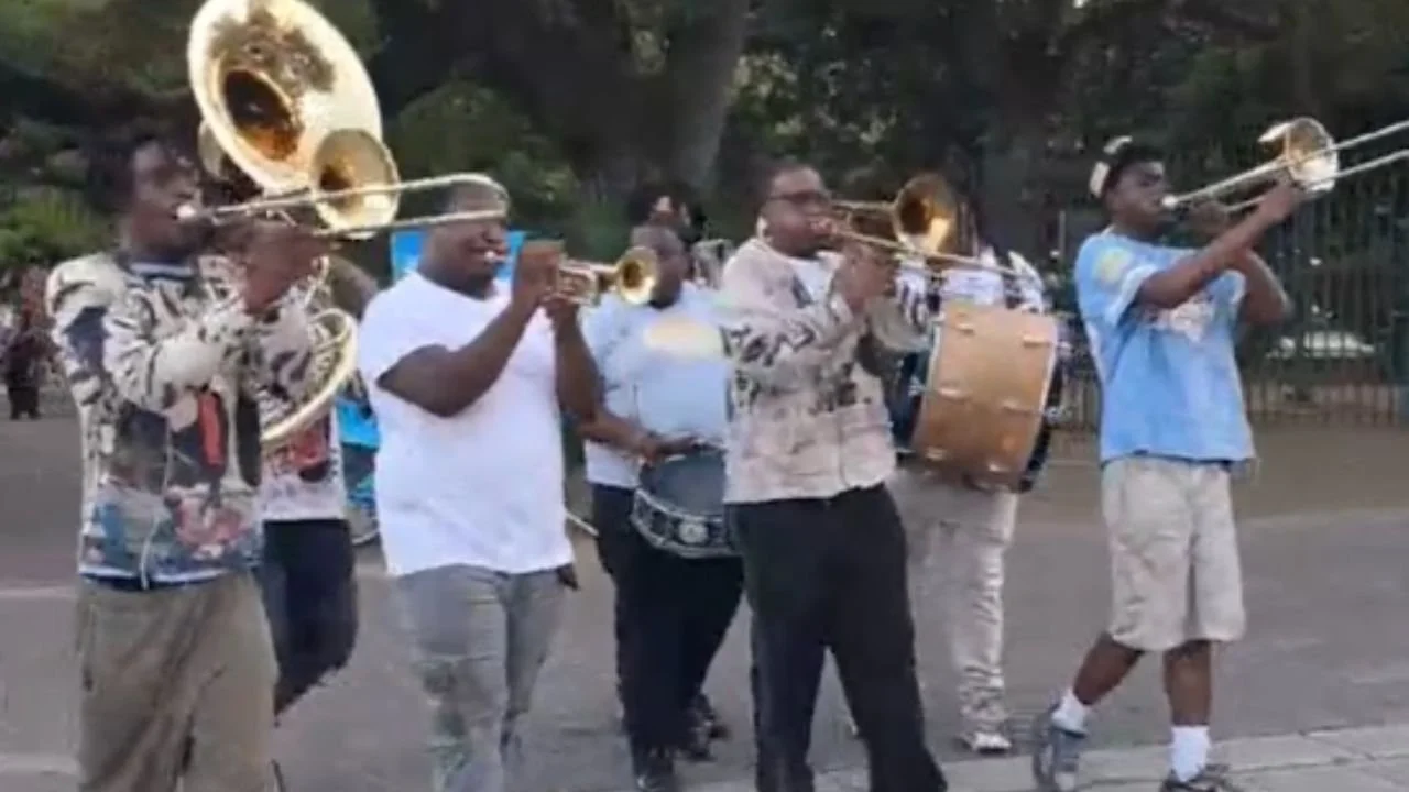 Second Line parade in New Orleans with a brass band marching through the street.