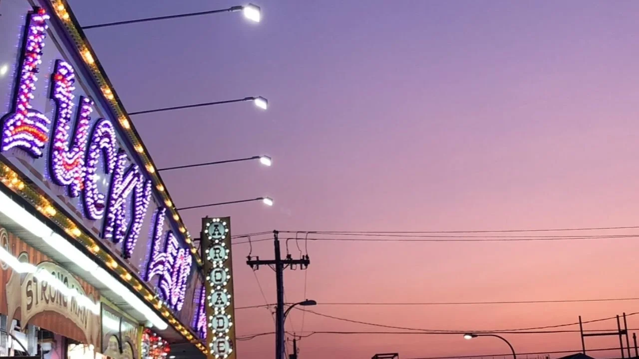 Glowing boardwalk arcade sign at dusk on the Jersey Shore, setting the mood for New Jersey cryptid legends