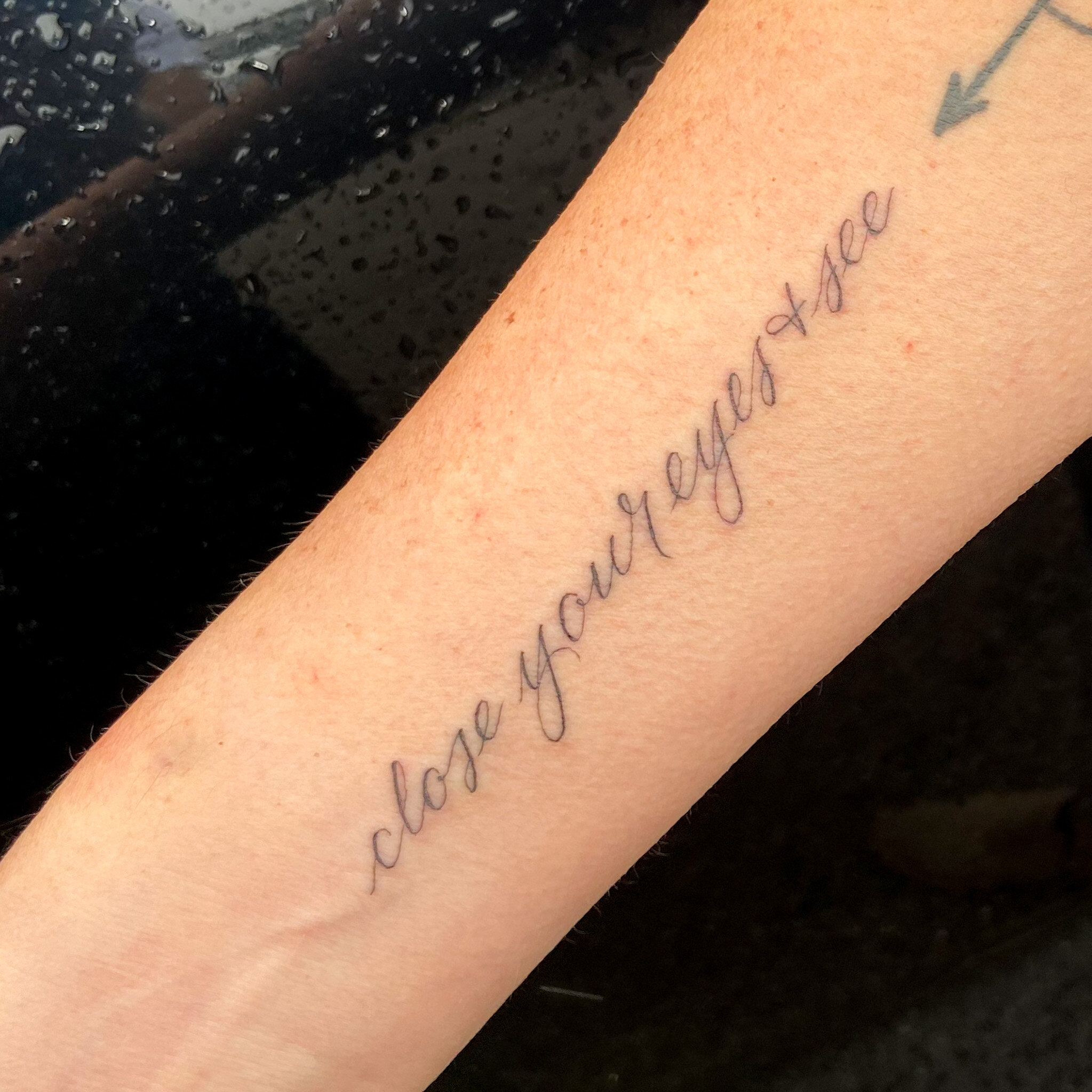  script lettering tattoo of the words “‘close your eyes and see” 