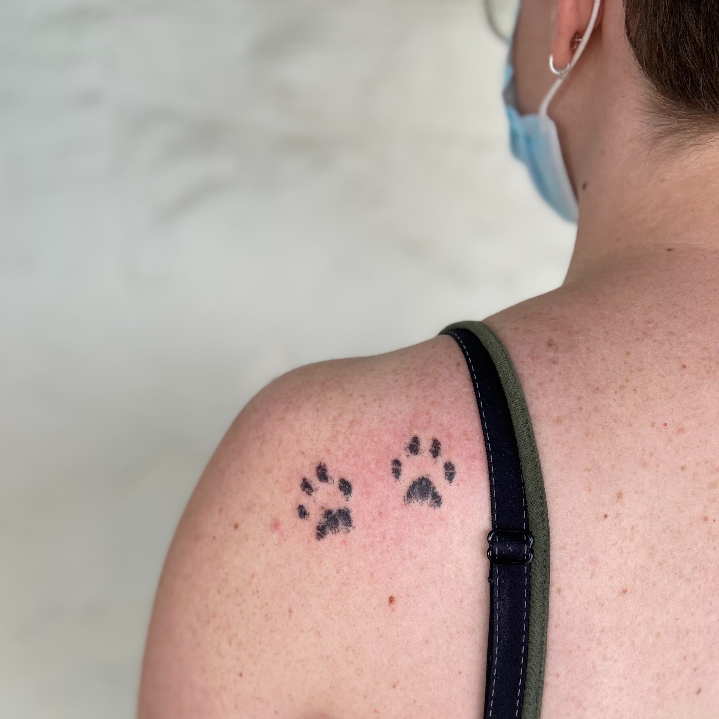  two paw prints tattood on a woman’s shoulder 