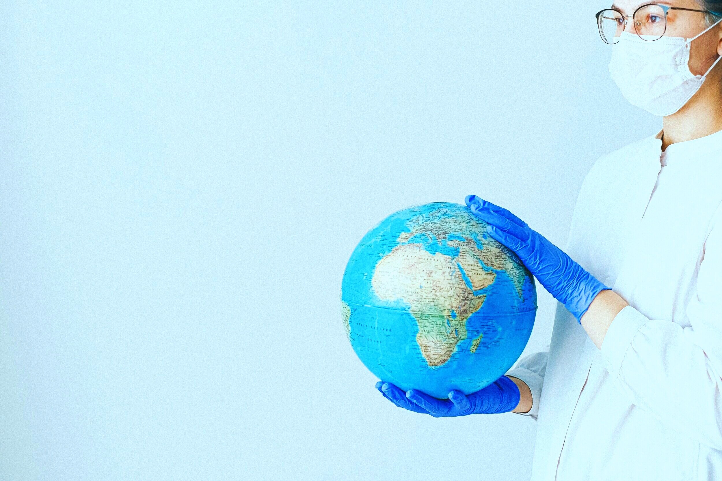 person-with-a-face-mask-and-latex-gloves-holding-a-globe-4167539.jpg