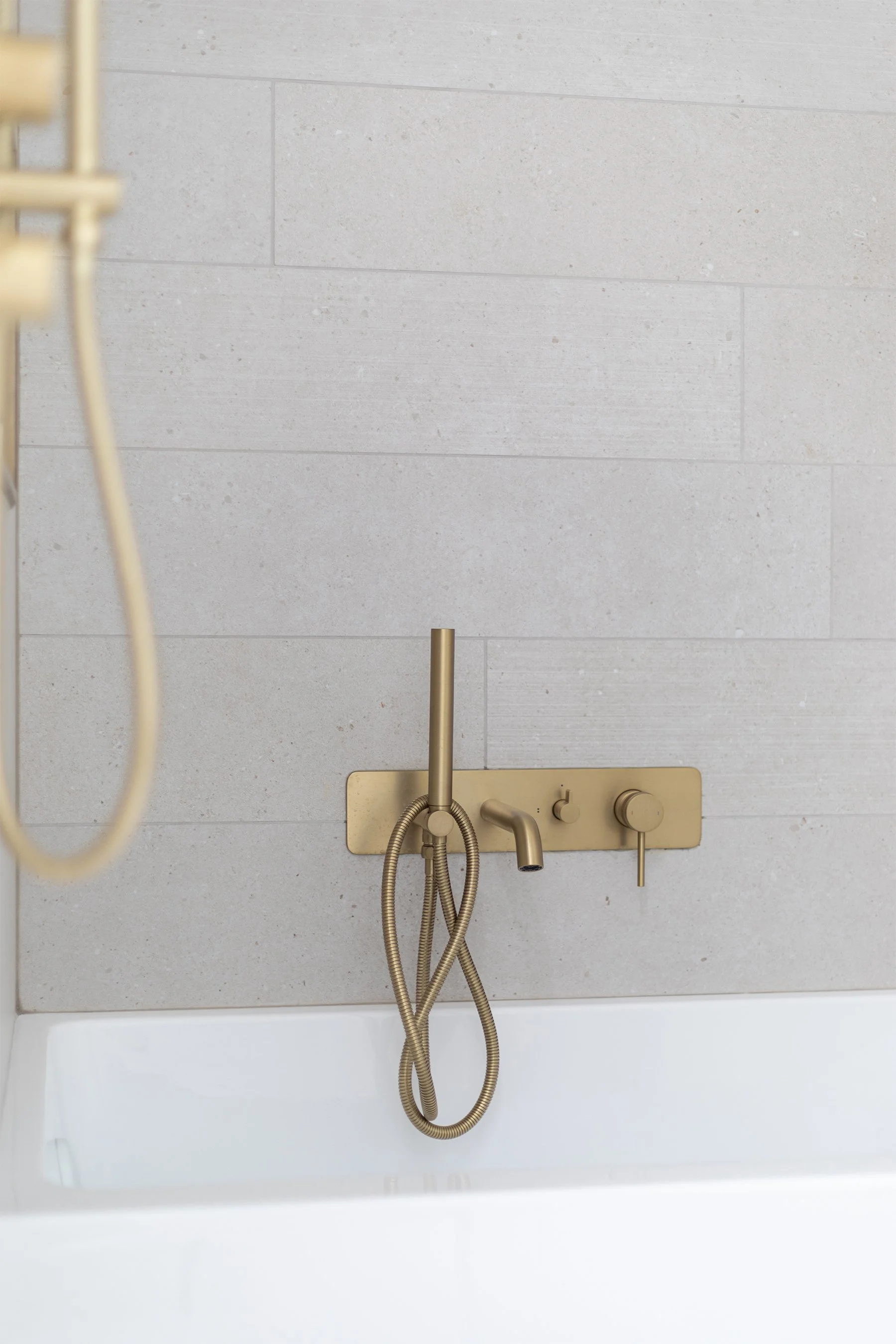 Mural de salle de bain avec robinetterie en laiton et parois en carreaux de céramique grise.