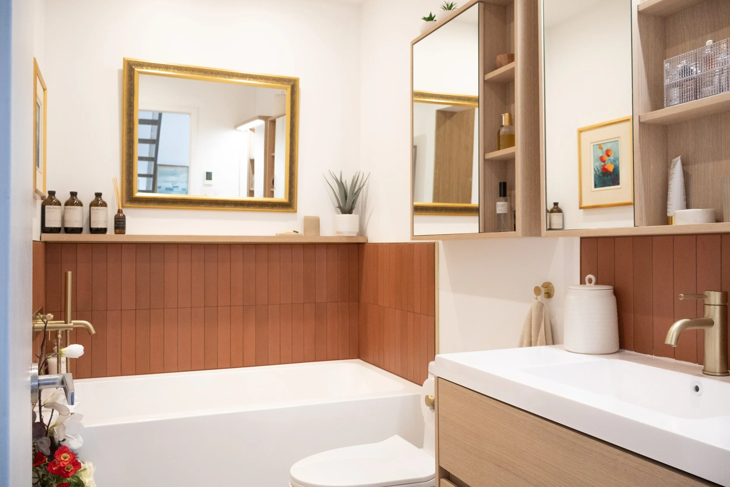 Salle de bain chaleureuse avec céramique de couleur terra cota et vanité en chêne blanc.