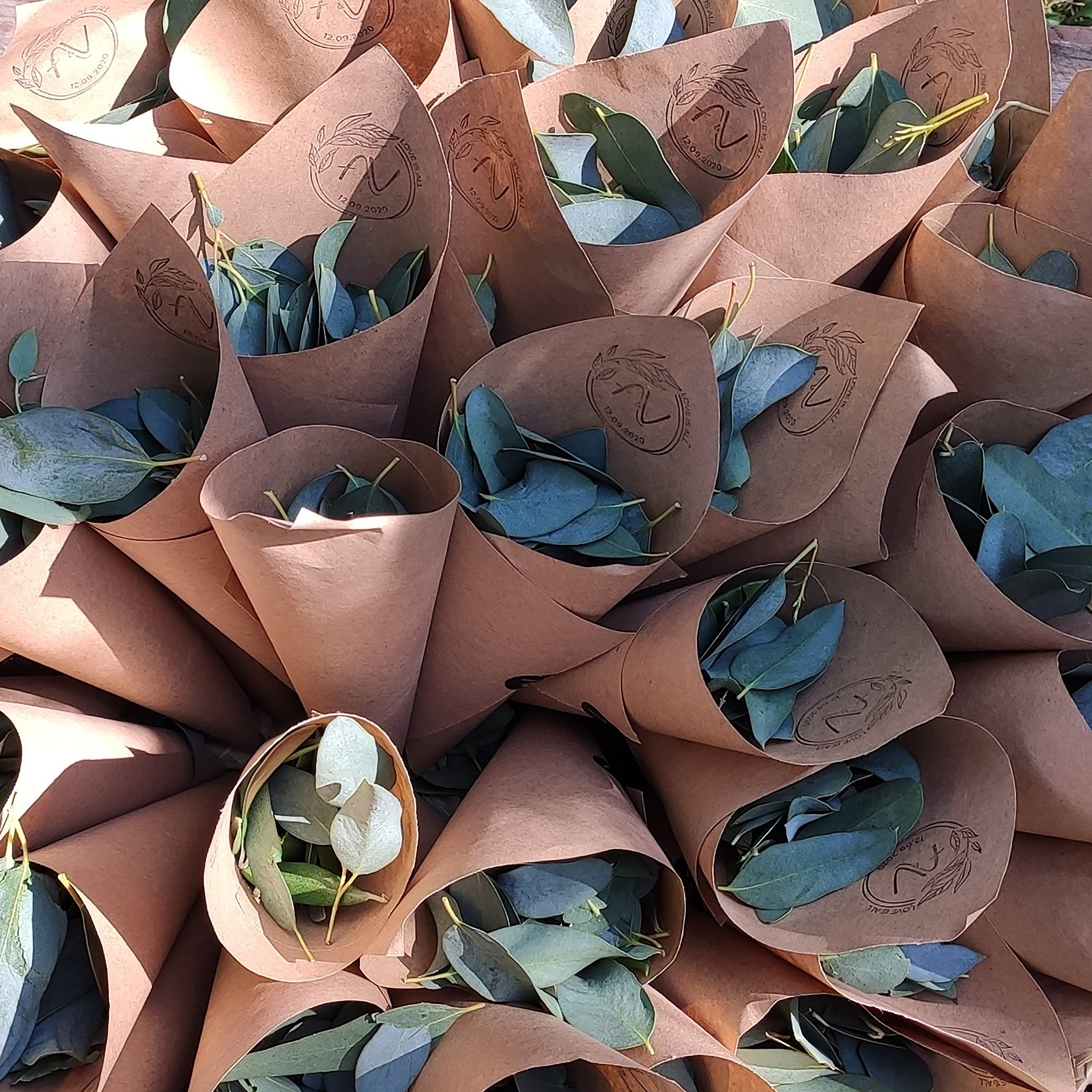 Bouquets d'eucalyptus enveloppés de papier kraft, avec le logo "Love is all".