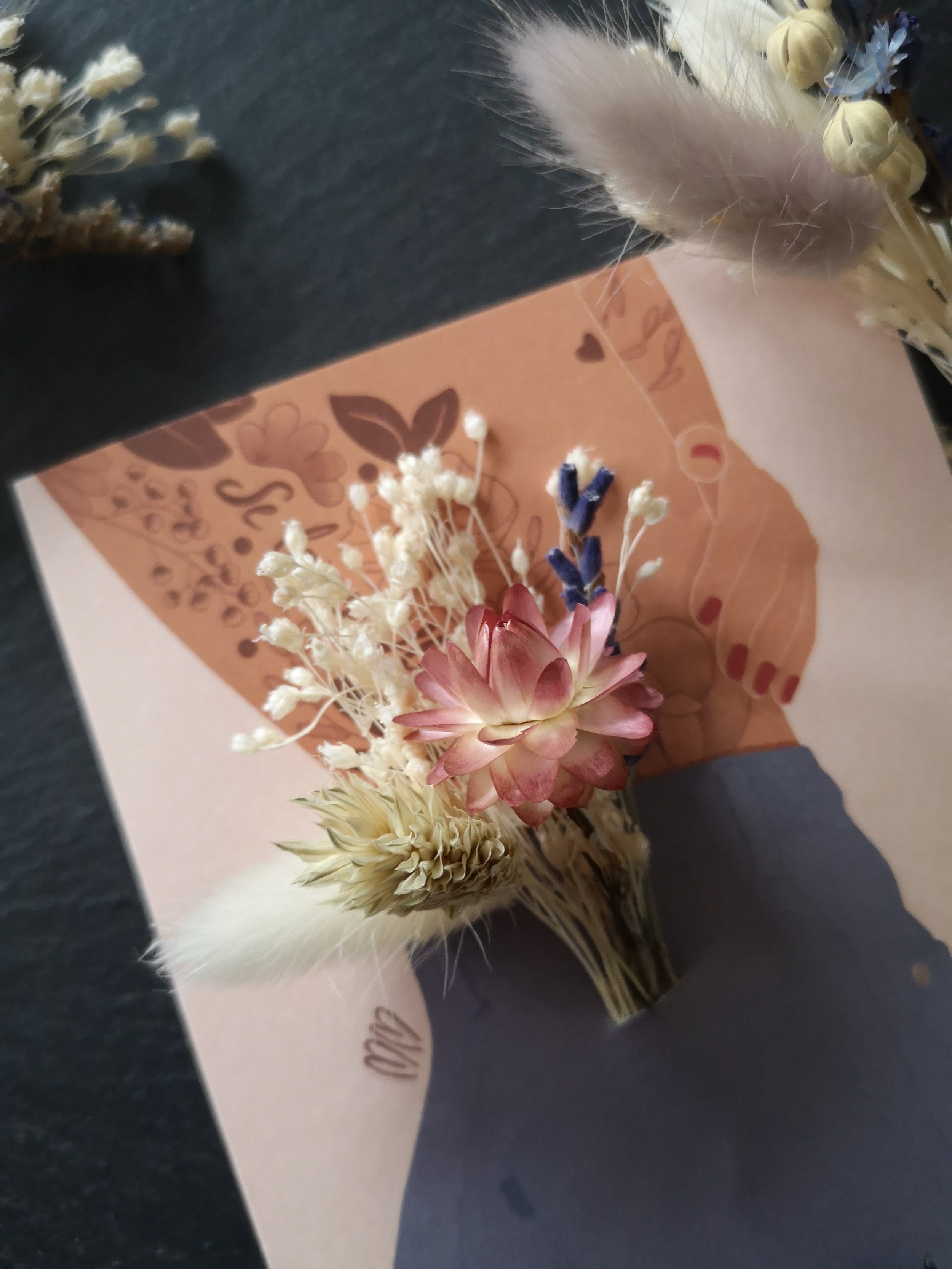 Carte illustrée d'une femme en jean avec placé dans la poche arrière de son pantalon un véritable bouquet de fleur séchées.