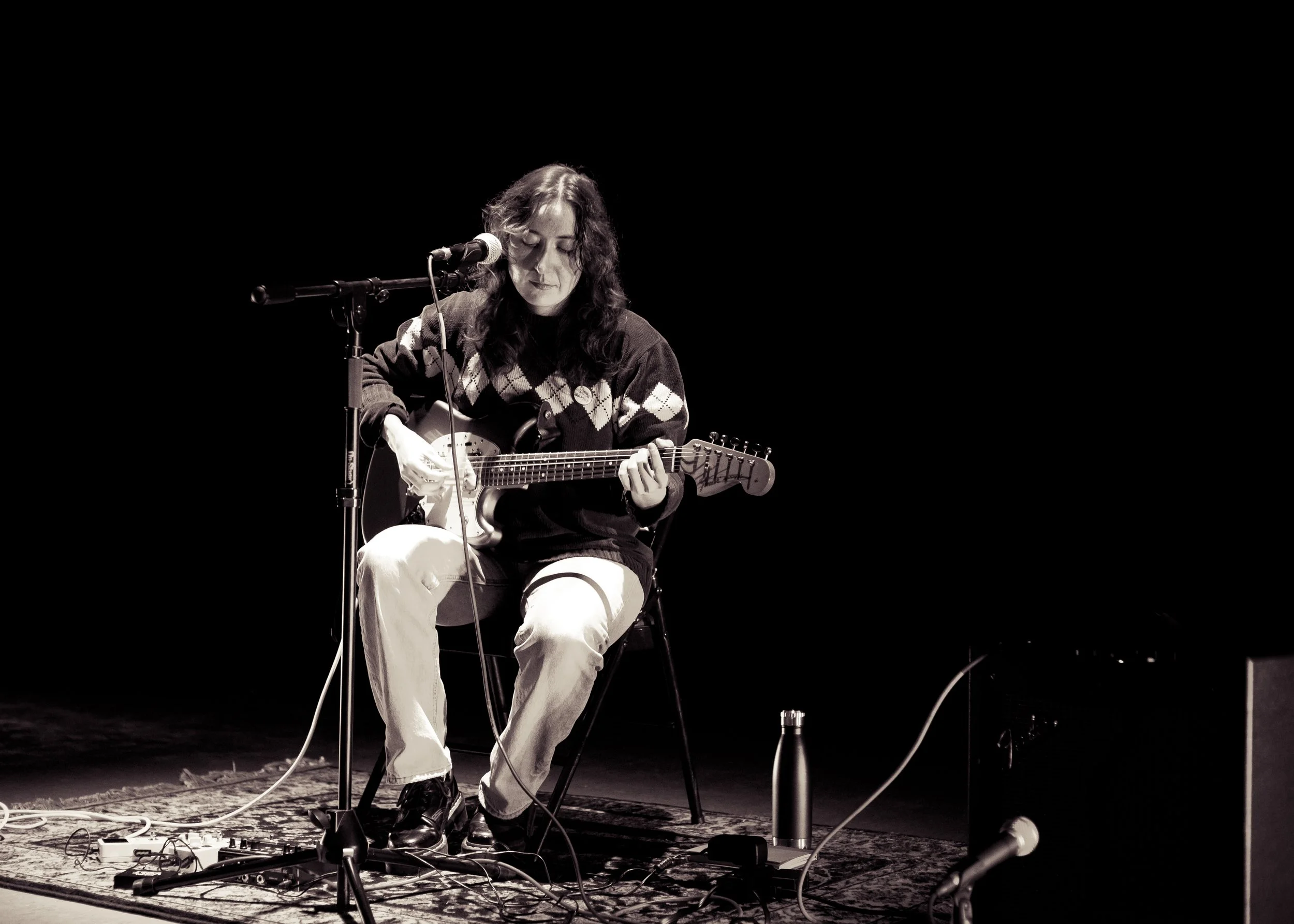 St. Moan playing guitar at the 2026 Queer Spectra Artist-in-Residence Showing