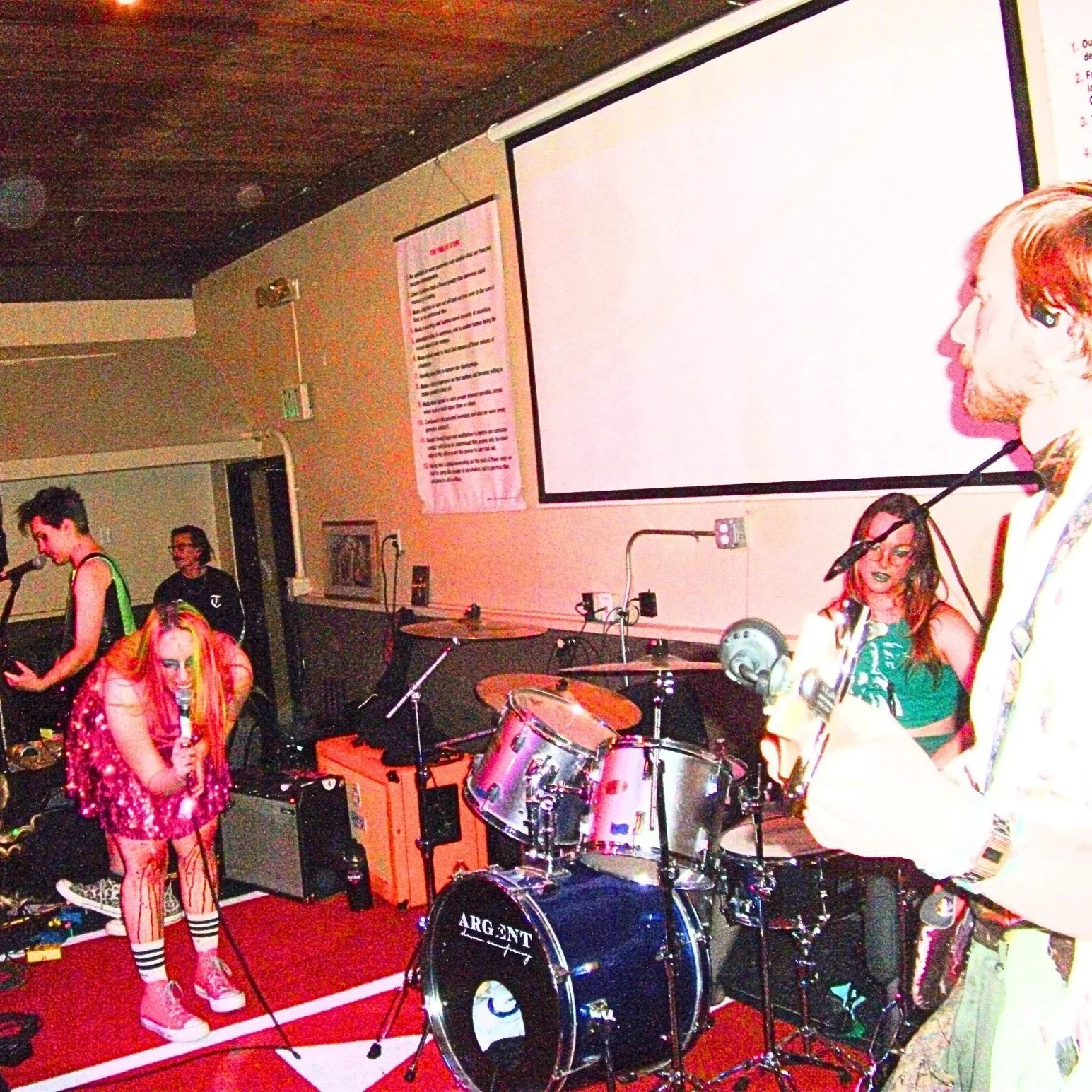 Venus Death Trap performs on a red, carpeted stage at the Fellowship Hall, all covered in blood and glitter. Sophi screams into the microphone while the crowd dances.
