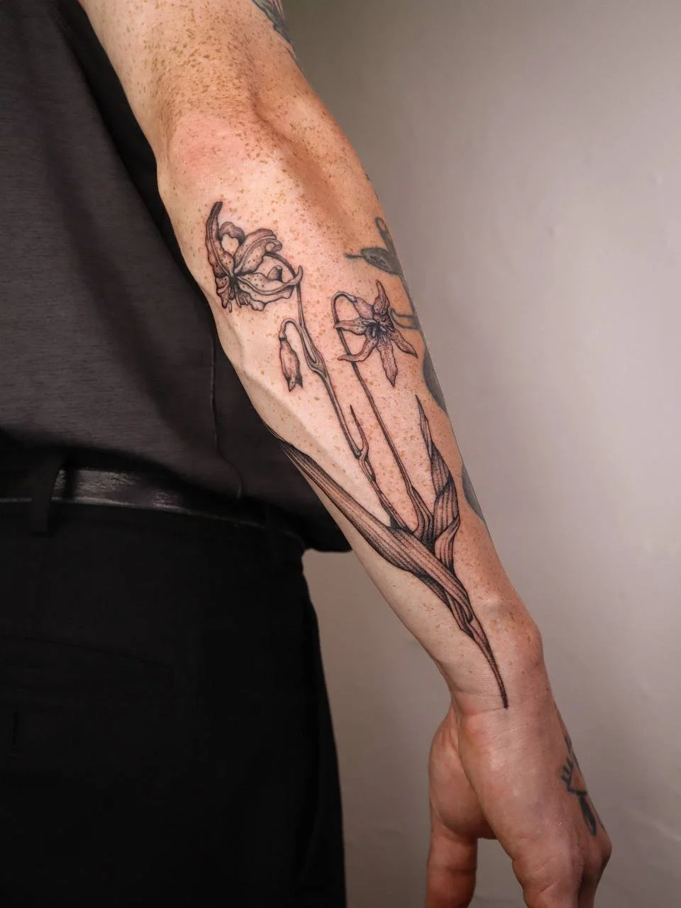 Floral fineline lily arm tattoo in Helsinki