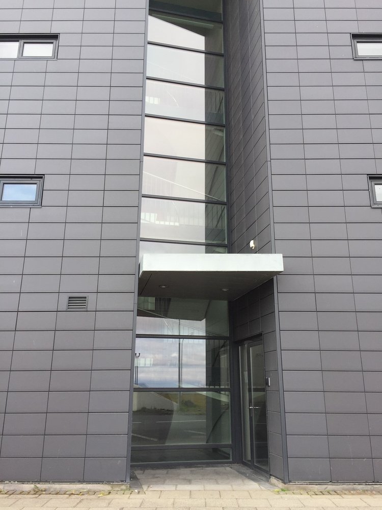 Modular cement siding panels protect this apartment building, while a recessed full height panel of glass allows for natural light in the common staircase. Image courtesy of Rich Granoff