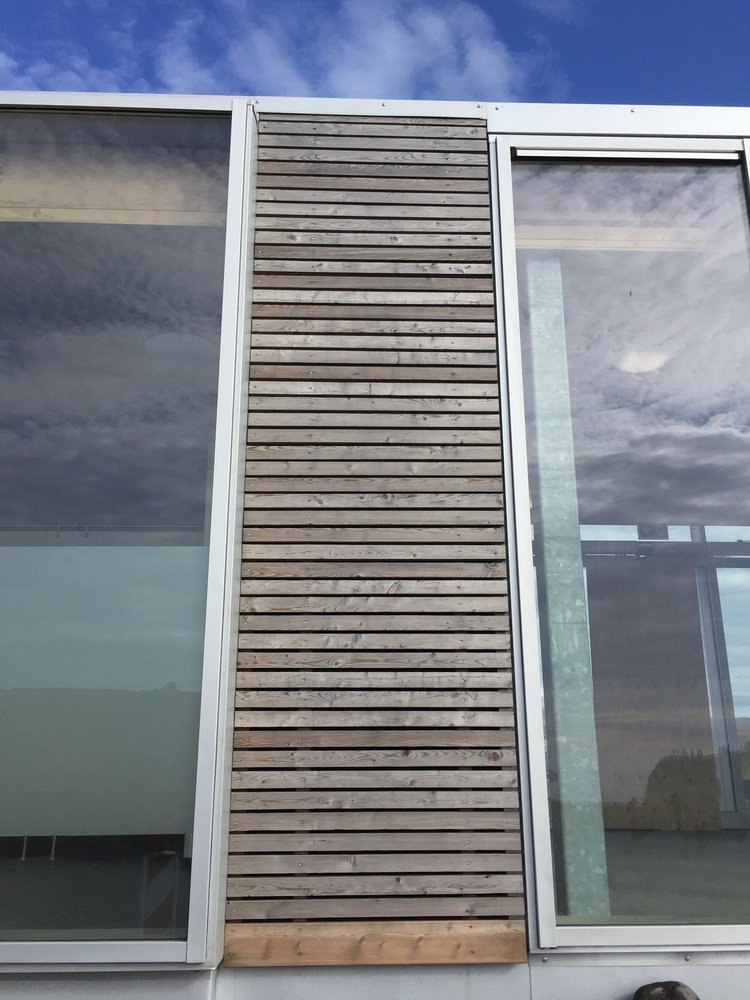 Alternating wood slats and large glass panels on a house by the sea provide protection while maximizing views. Image courtesy of Rich Granoff