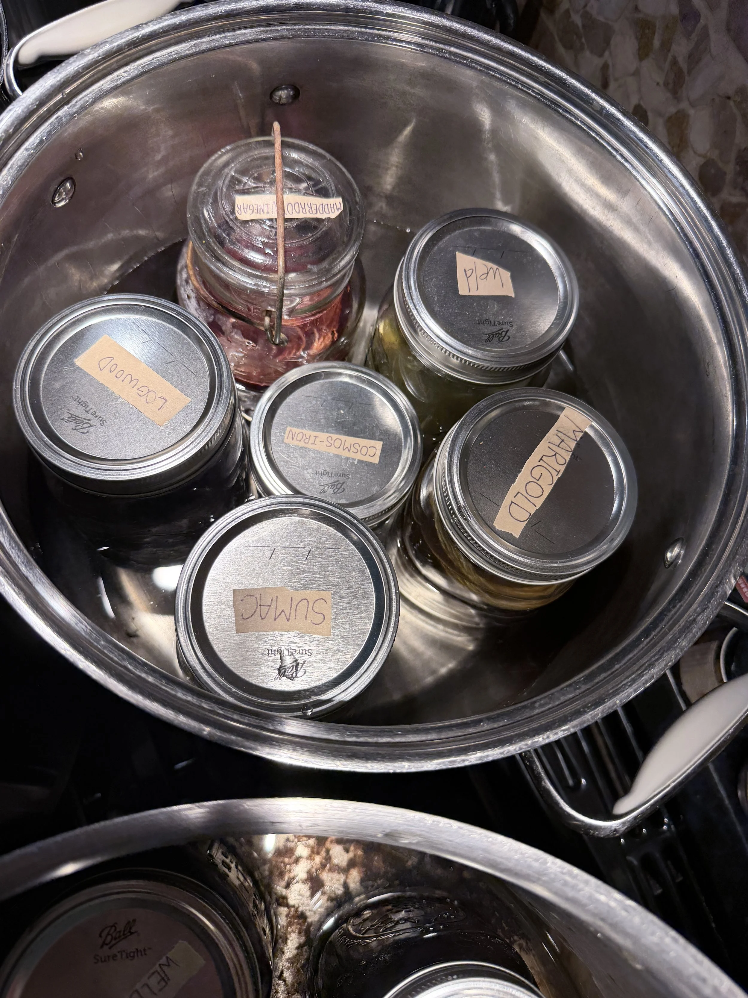 Large cooking pot with several different dye jars simmering inside.
