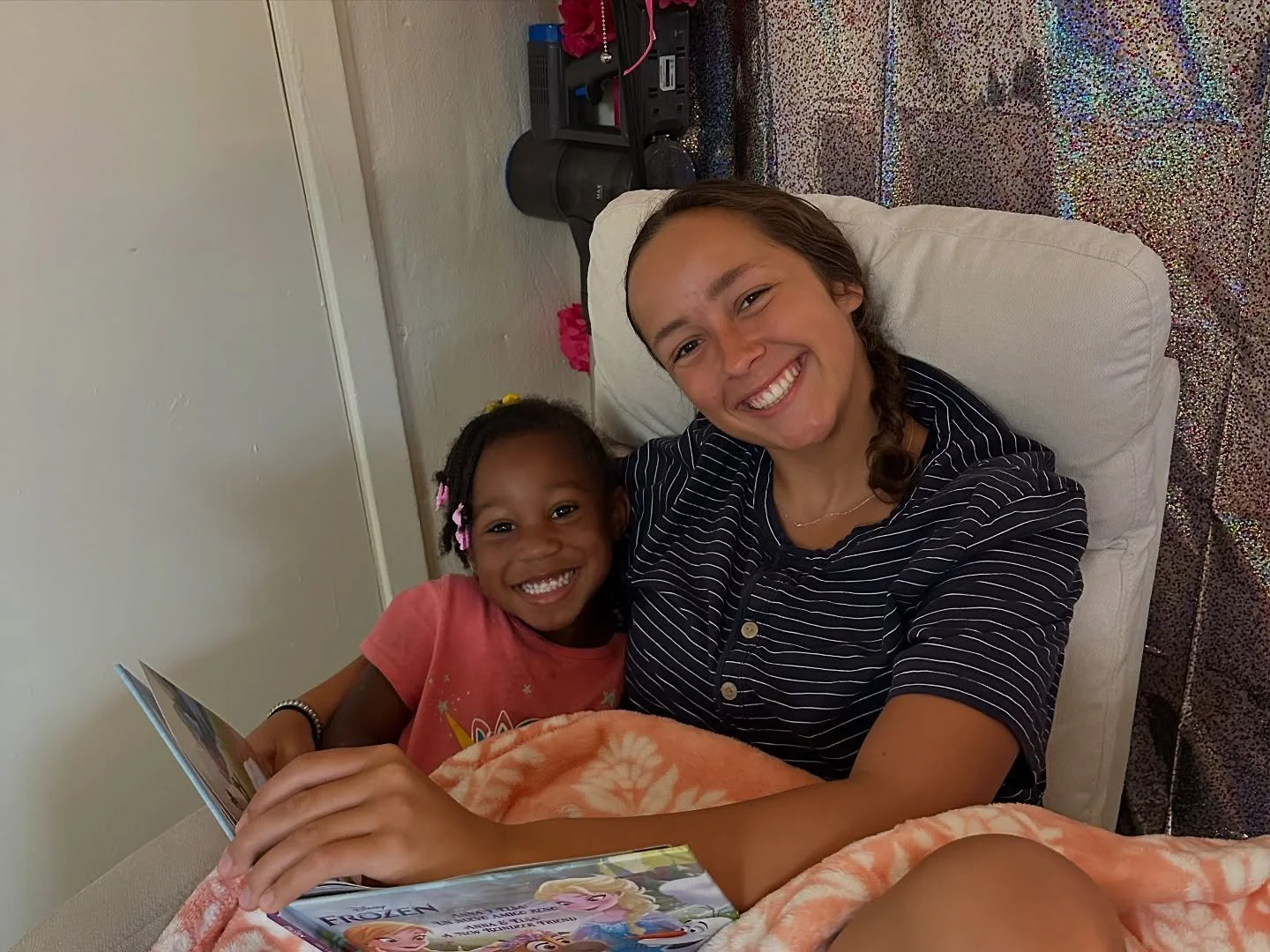 a social worker sitting with a young child reading a book