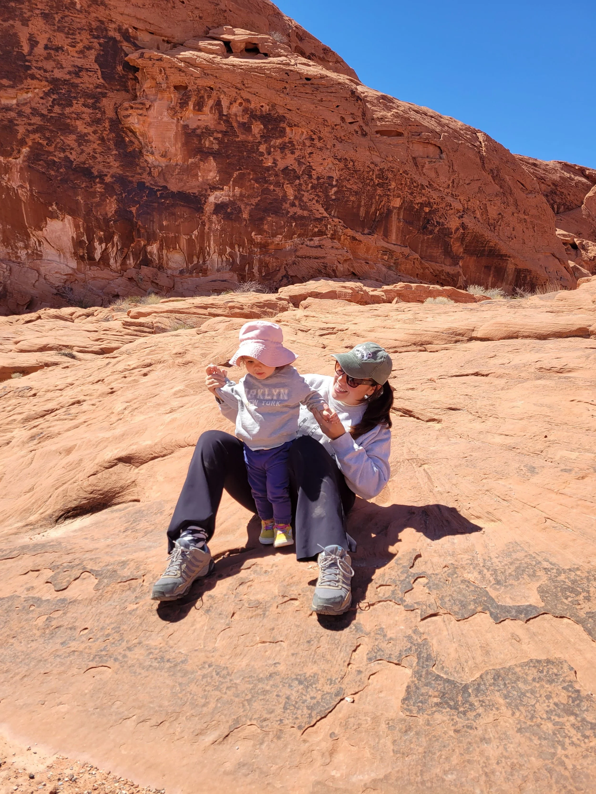 Woman and child sitting in Red Rock Canyon. Wearing hats on a bright day.