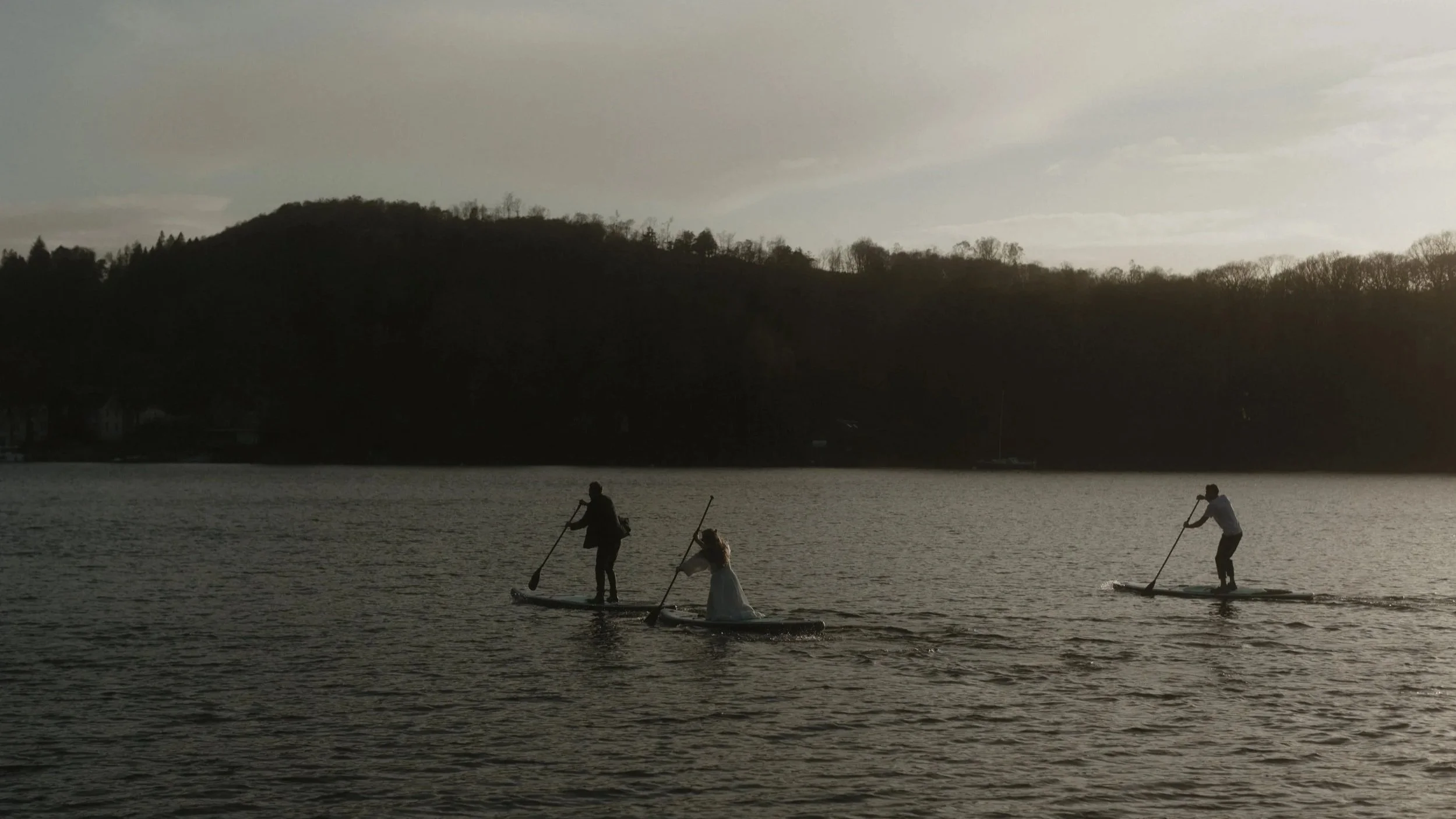 A bride and groom paddle boarding on a lake at sunset with their guests a truly unique wedding moment at town head wedding estate