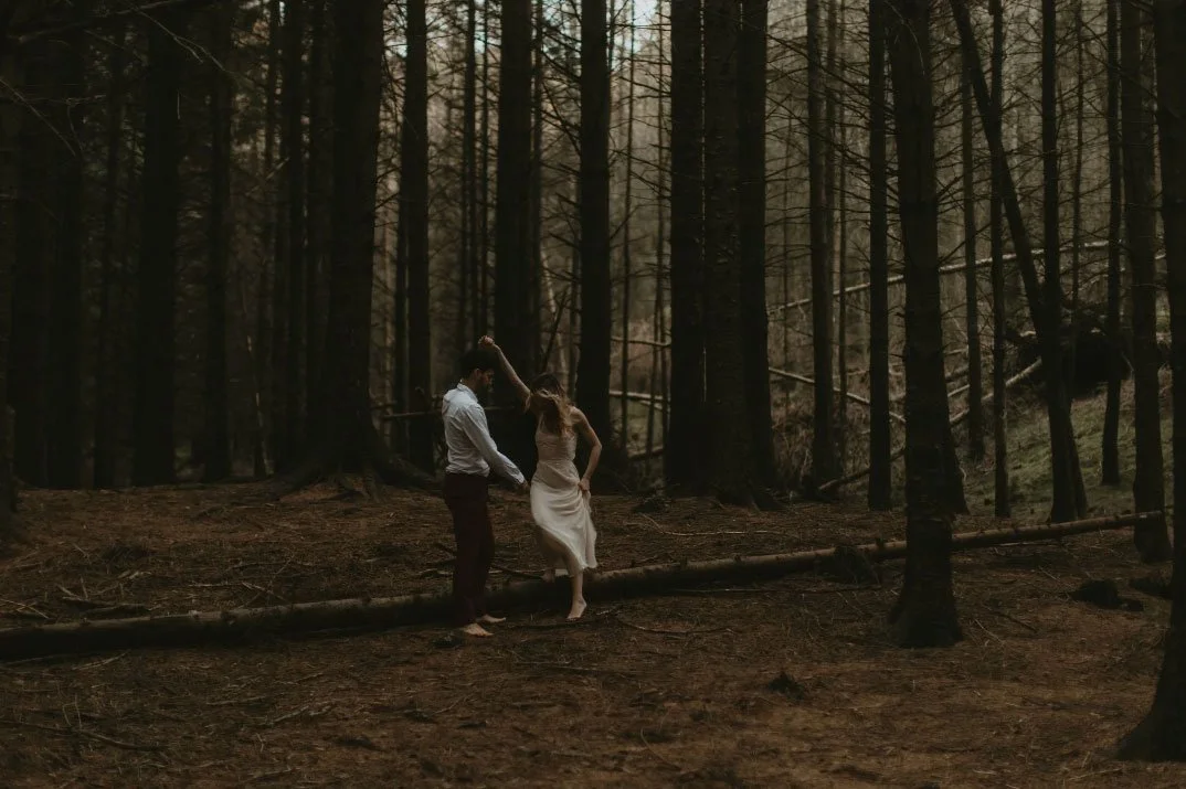 barefoot couple on their elopement wedding day dancing through trees with a pledge to donate to reforestation scheme responsible photographer