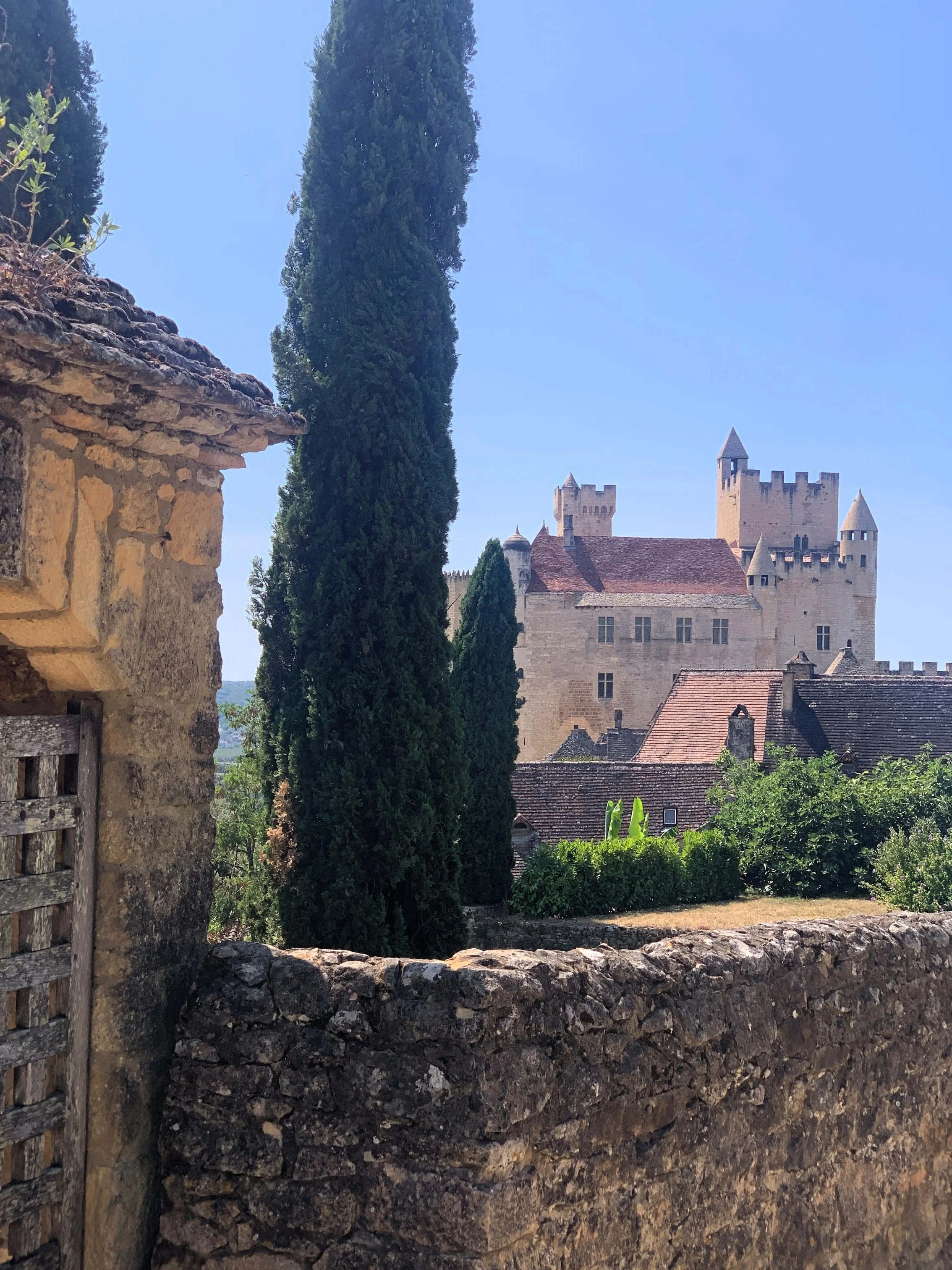 A view over a low stone wall of a medieval stone castle in the background.