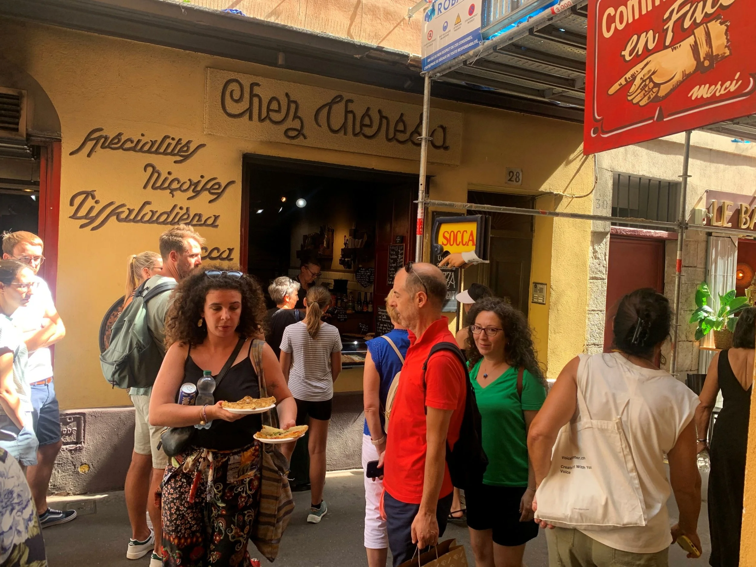 The front of a restaurant with the words Chez Thérésa printed above a window where people are ordering at the counter.
