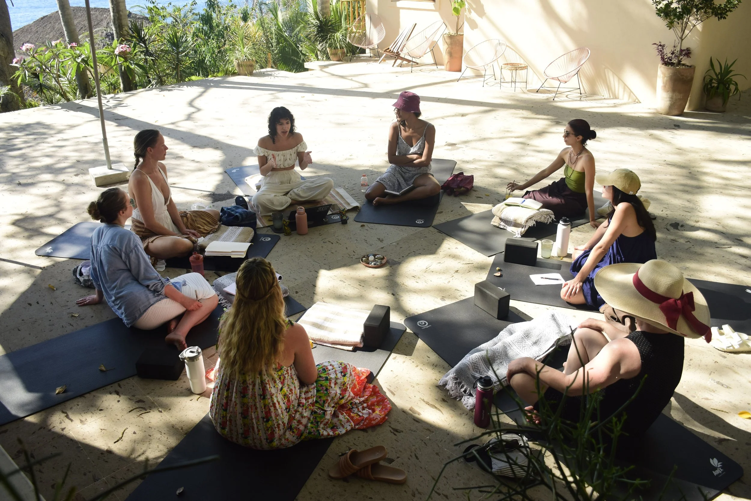 Group sitting in a circle on mats during an outdoor sound healing and breathwork session