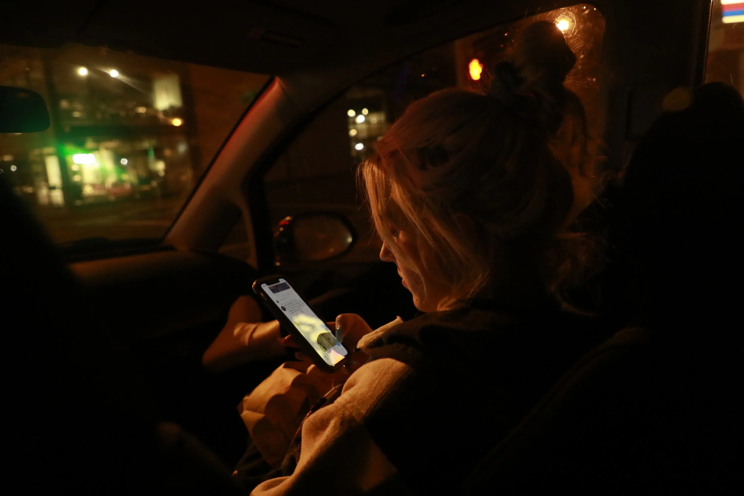  Naomi checks her phone on the drive home after her shift. She usually gets a ride from one of the other dancers or calls an Uber, as her own car is unreliable. 