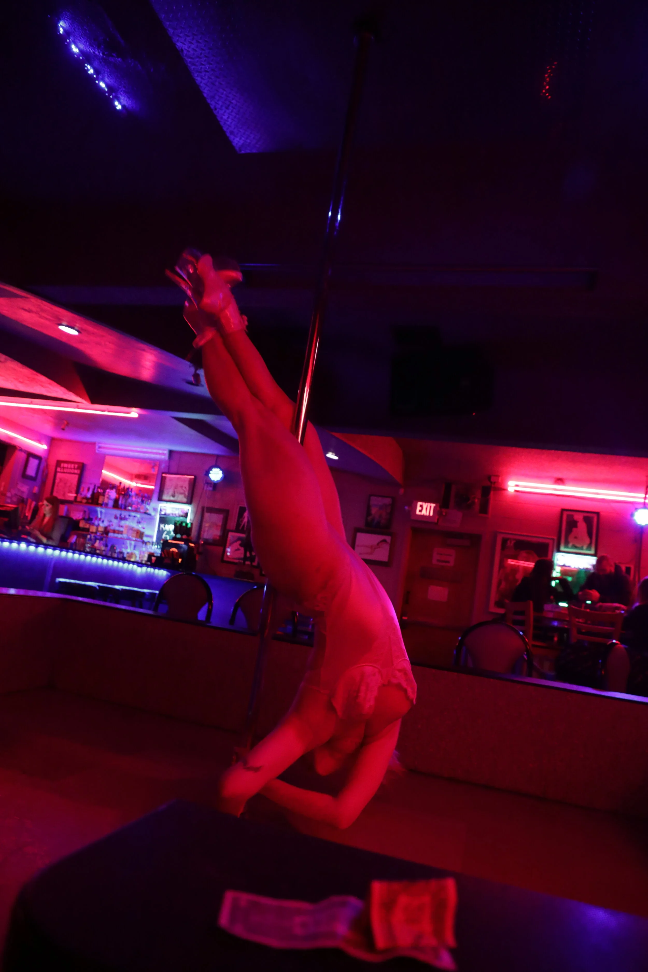  Naomi performs a pole trick at Sweet Illusions Gentlemen’s Club in Springfield, while a tip from the last customer of the night lies in front of her. Naomi says she had never touched a pole in her life when she started the job, and had to learn enti