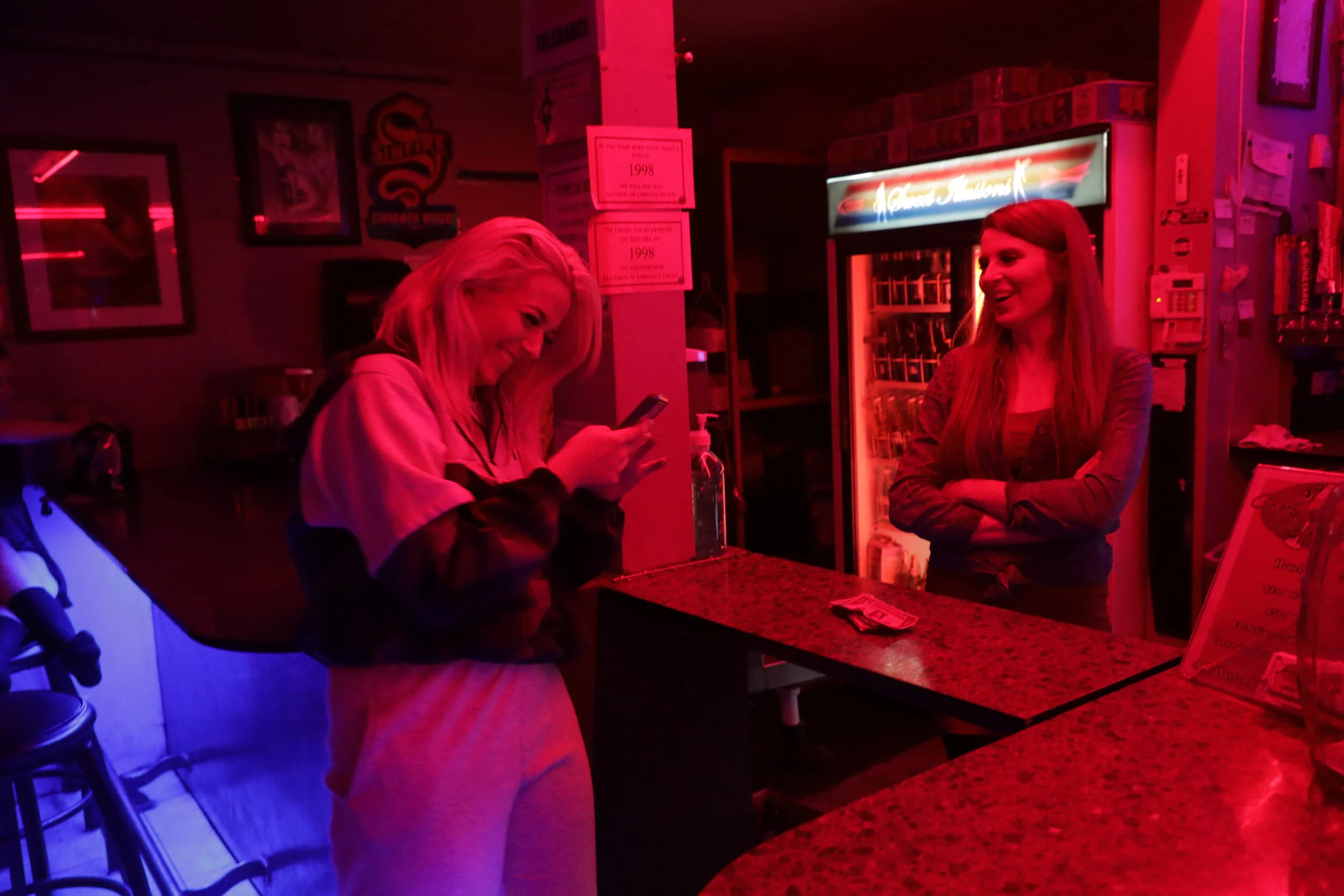  Naomi giggles over a picture of her new boyfriend with the bartender at Sweet Illusions, Shawnda Wasson. Dancers are encouraged to split 15% of their earnings at the end of the night with the bartender and bouncer, though Naomi admits she tends to g