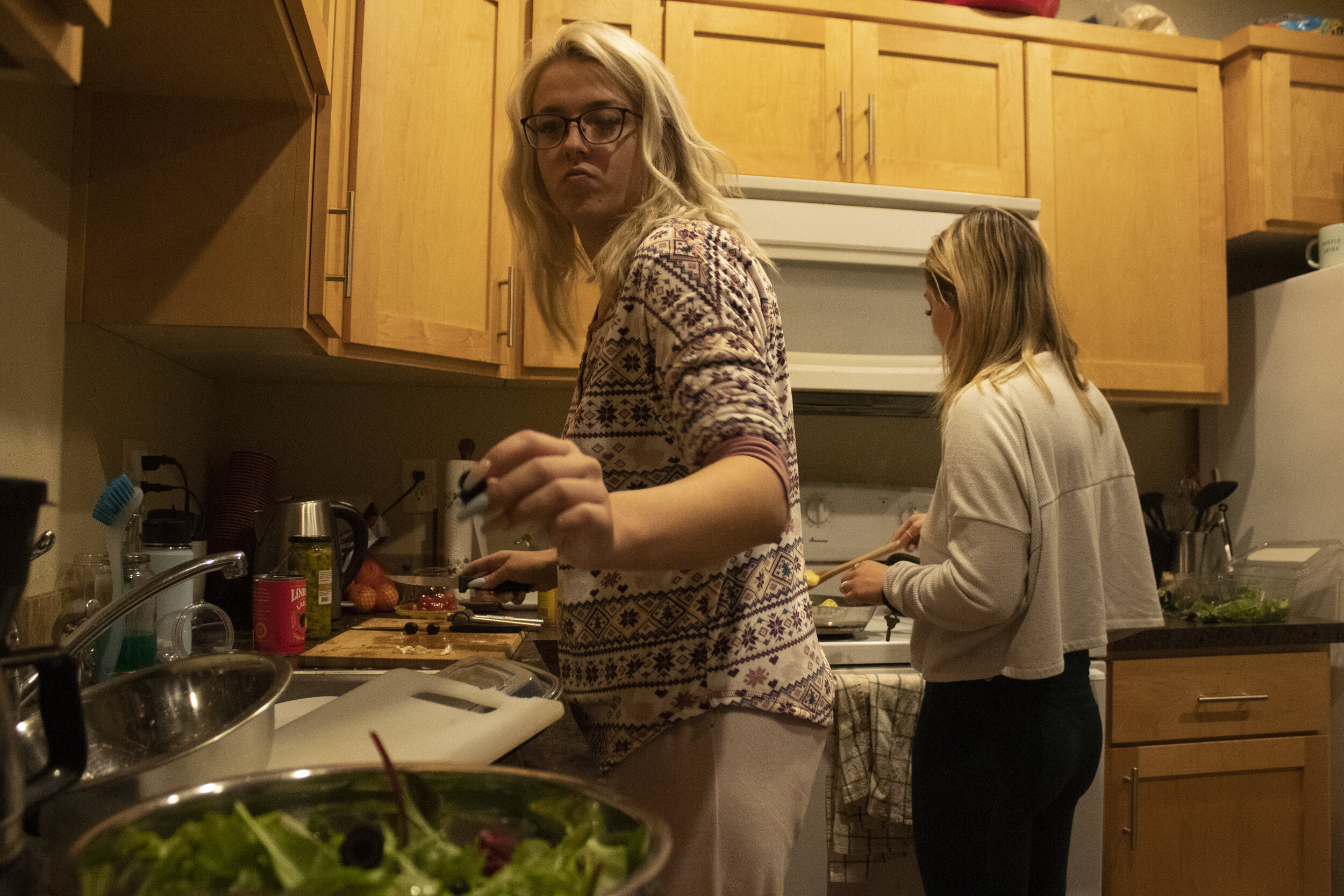 Naomi adds an olive to a homemade salad while Kira, right, stirs a pasta dish in their shared kitchen in Eugene. Naomi and Kira have both been vegan for more than a year, and enjoy cooking healthy meals together.