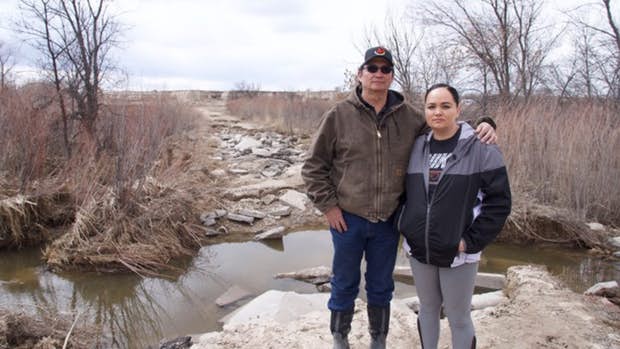 Pictured: Steve and Lacey Pourier standing on the road to their house on the Pine Ridge Reservation. The road is now rubble after they spent thousands to upgrade it.(Photo: Chuck Banner, Lakota People’s Law Project)
