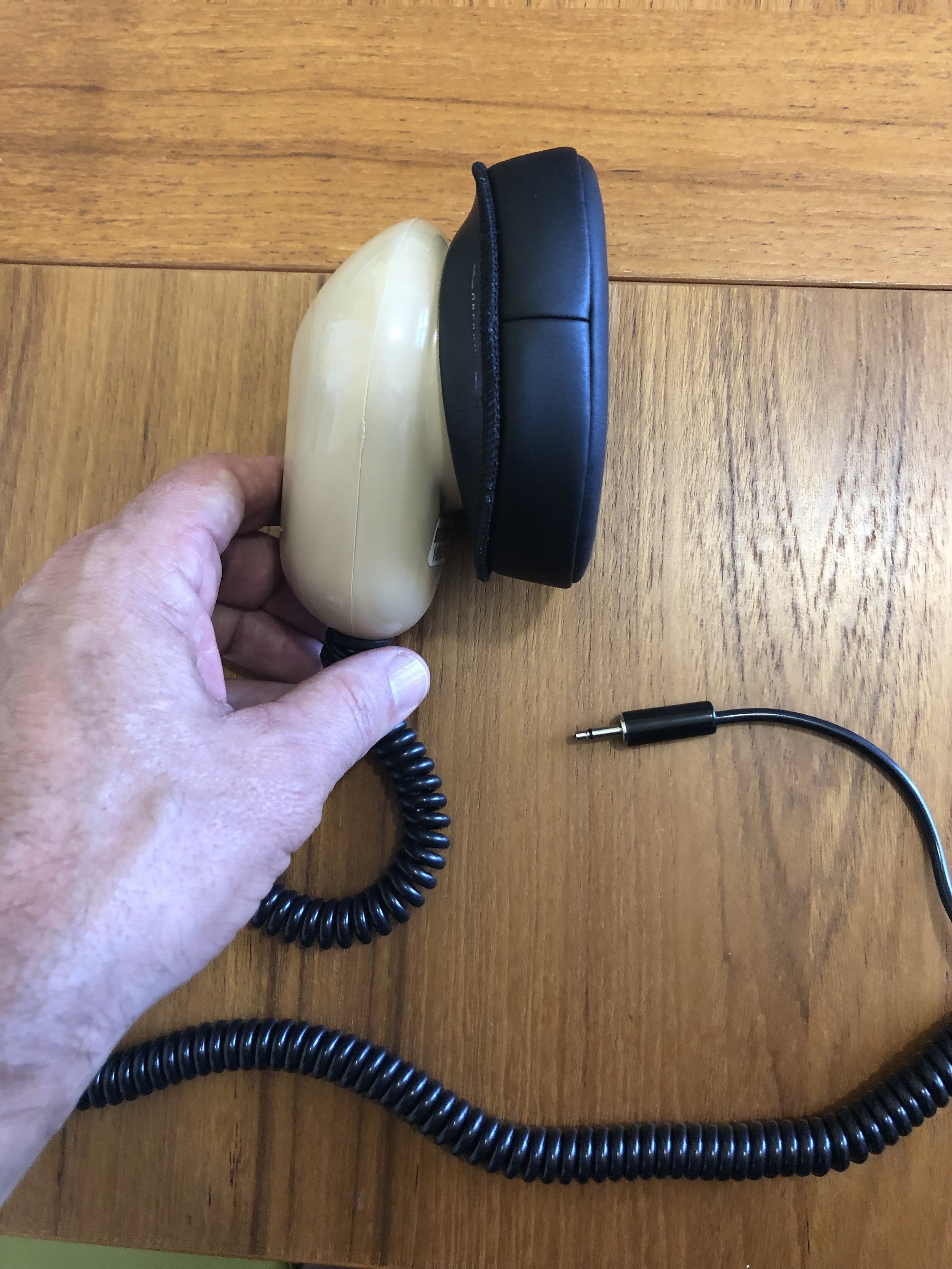 [Hand holding a stenographer's mask&nbsp;a mouth sized metal case with a flexible seal that fits around the mouth and contains a microphone. It is approximately the size of the hand.]