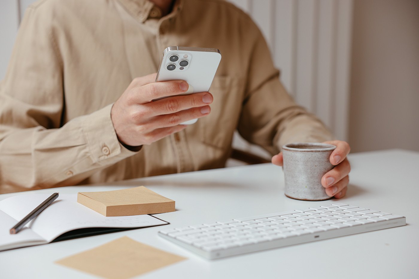man-holding-phone-at-desk-with-laptop.jpg