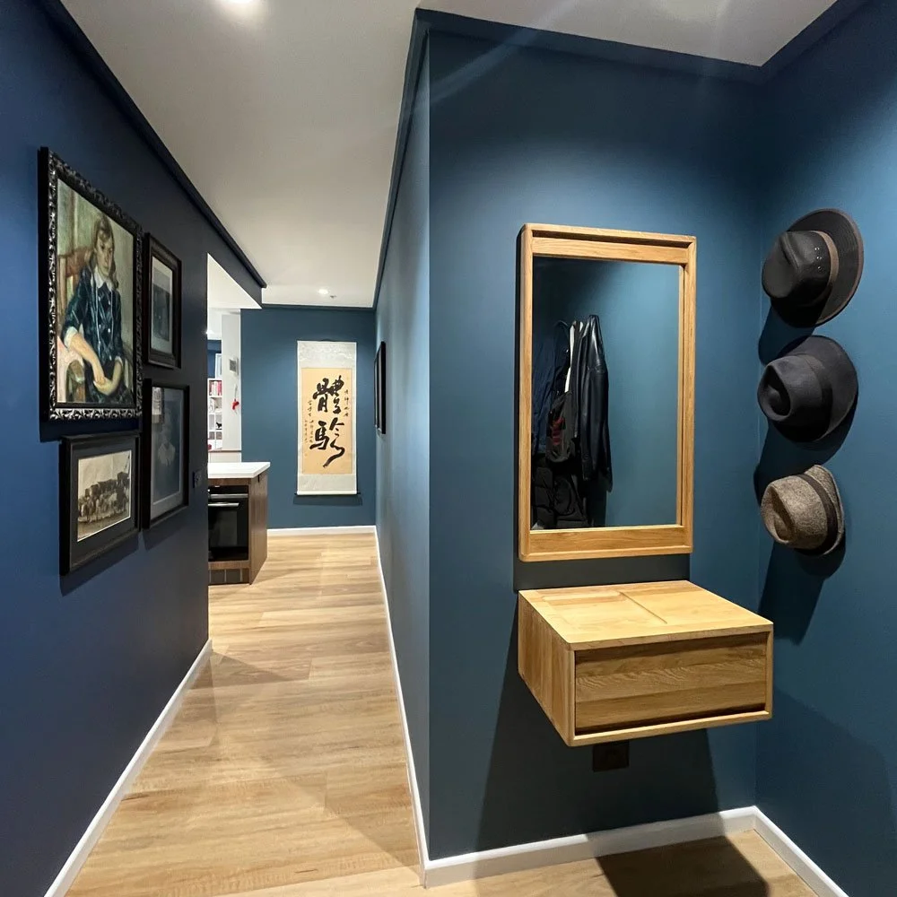 Blue apartment entry with timber floor and floating shelf with mirror