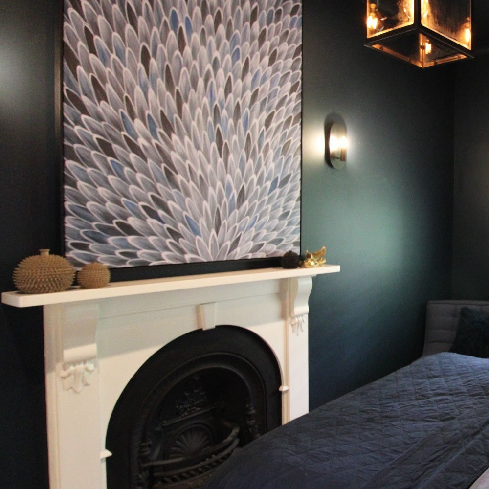 Boys bedroom with dark blue walls, large blue feathered art c anvas above a fireplace and large carriage pendant light above the boys bed, designed by Hue and Space Interior Design North Melbourne