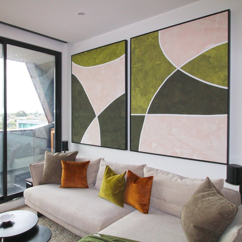 Two large geometric art canvases hang over a sofa to make the sofa feel smaller