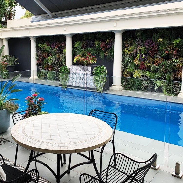 Pato table and chairs by the pool showing green wall in the background designed by Hue and Space Interior Design