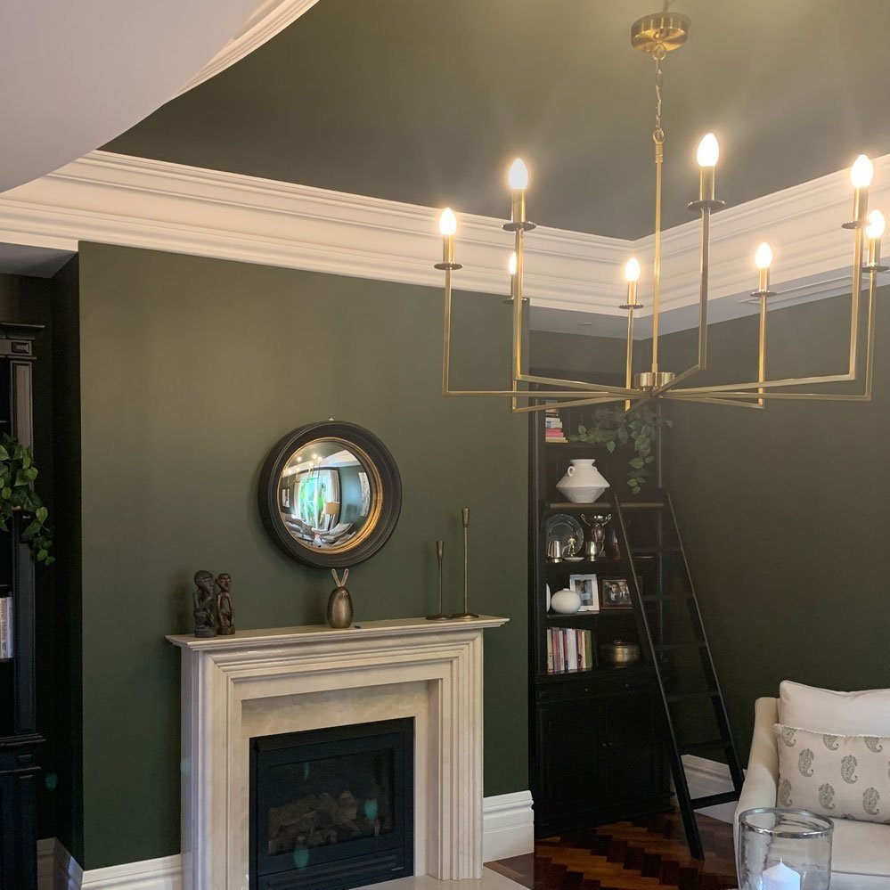 Marble fireplace with large brass chandelier, olive green walls and neutral fabirc chair, living room designed by Hue and Space Interior Design