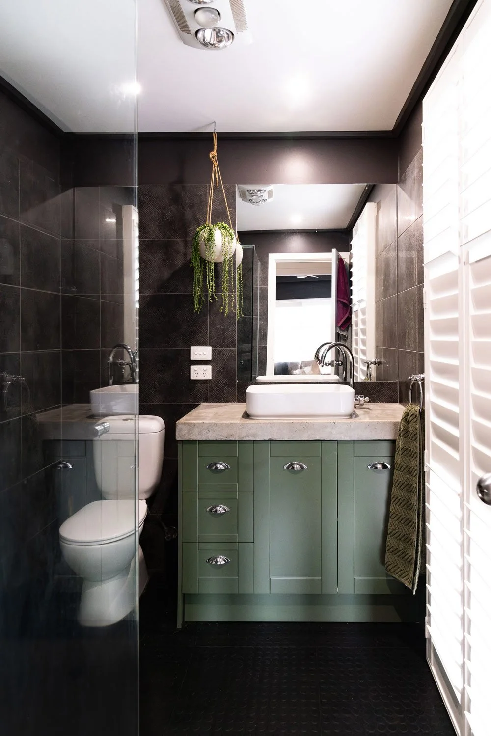 green bathroom with chrome hardware and dark tiles