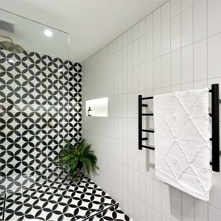Black and white tile on floor and wall of shower with white subway tiles designed by Hue and Space Interior Design