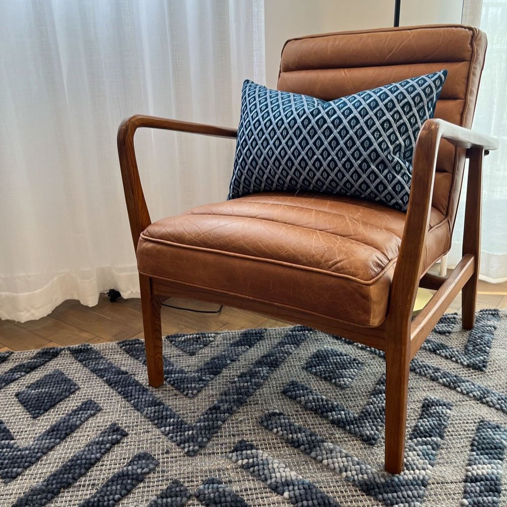 Leather living room chair with blue cushion sitting on blue rextured rug designed by Hue and Space Interior Design