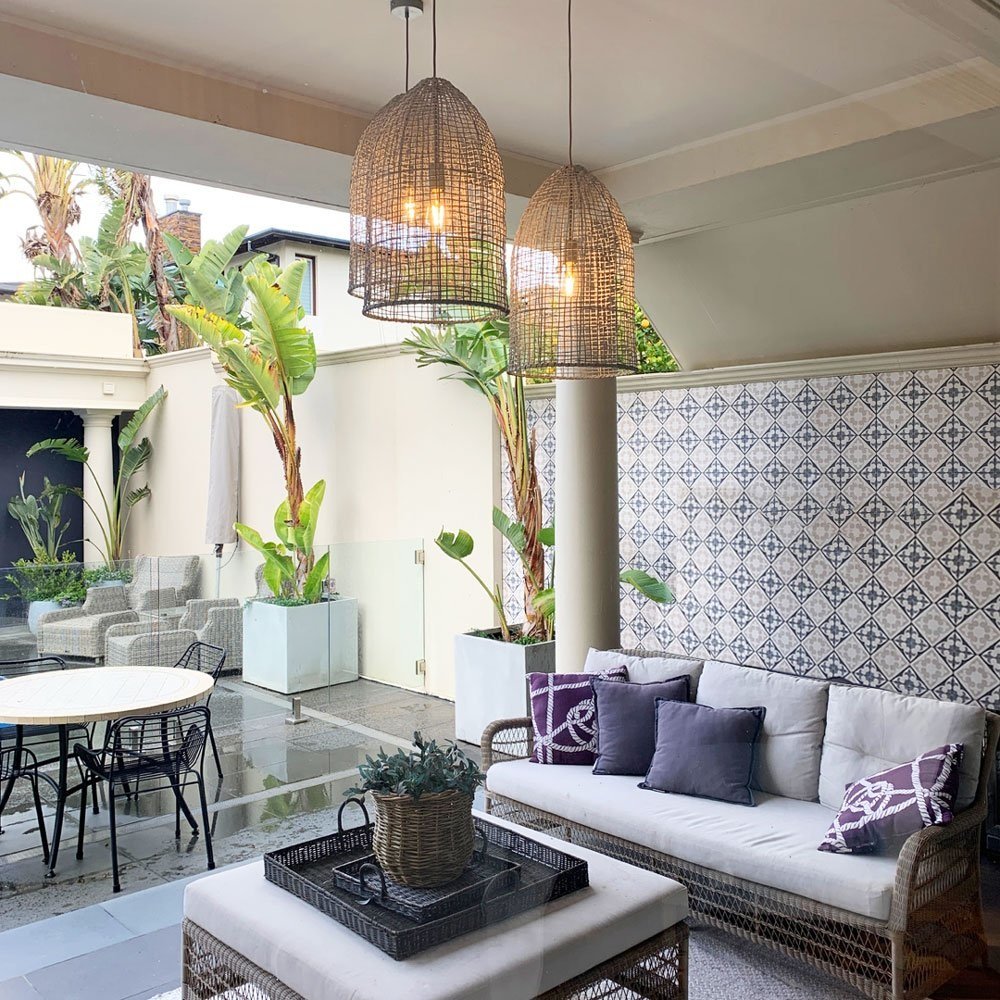 Large rattan pendant lights hung in outdoor patio with tiled wall behind designed by Hue and Space
