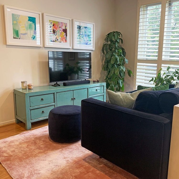 Navy velvet sofa and pink rug with colourful artwork designed by Hue and Space Interior Design
