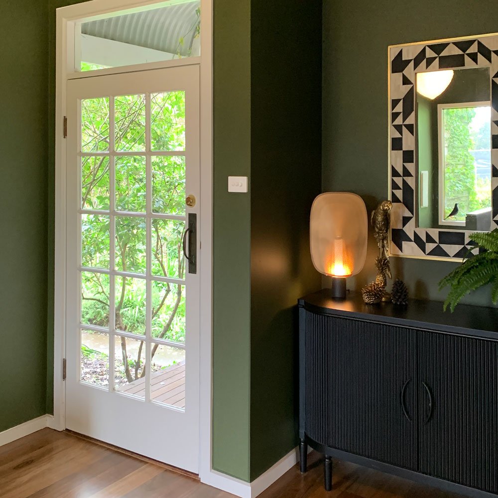 Green painted walls, bone inlay mirror and reeded timber sideboard in black, decorate this entry makeover by Hue and Space Interior Design