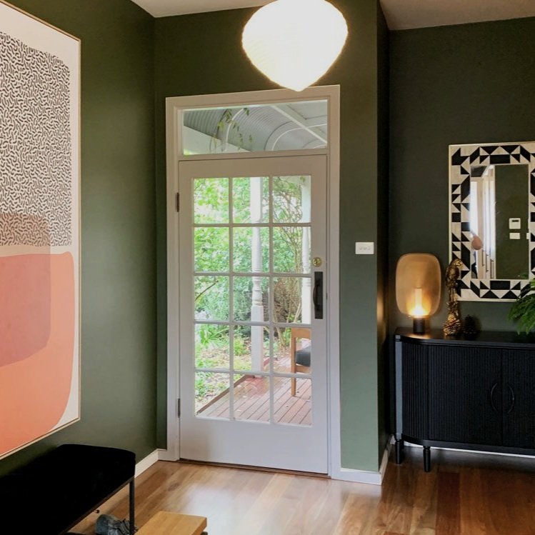 Bone inlay mirror sits over black sideboard with brass light in this entry way made over by Hue and Space Interior Design