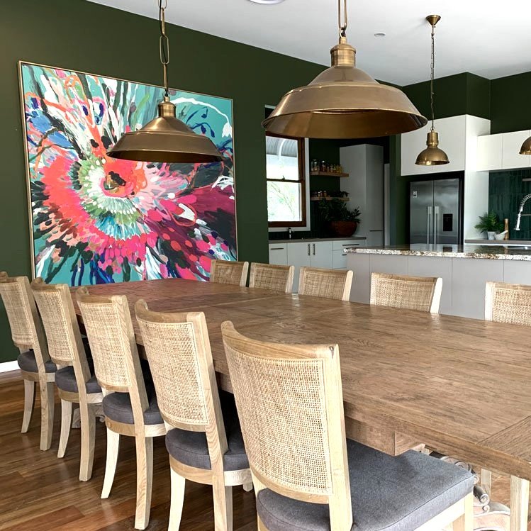A large, colourful art canvas anchors the dining table next to the kitchen make-over by Hue and Space Interior Design