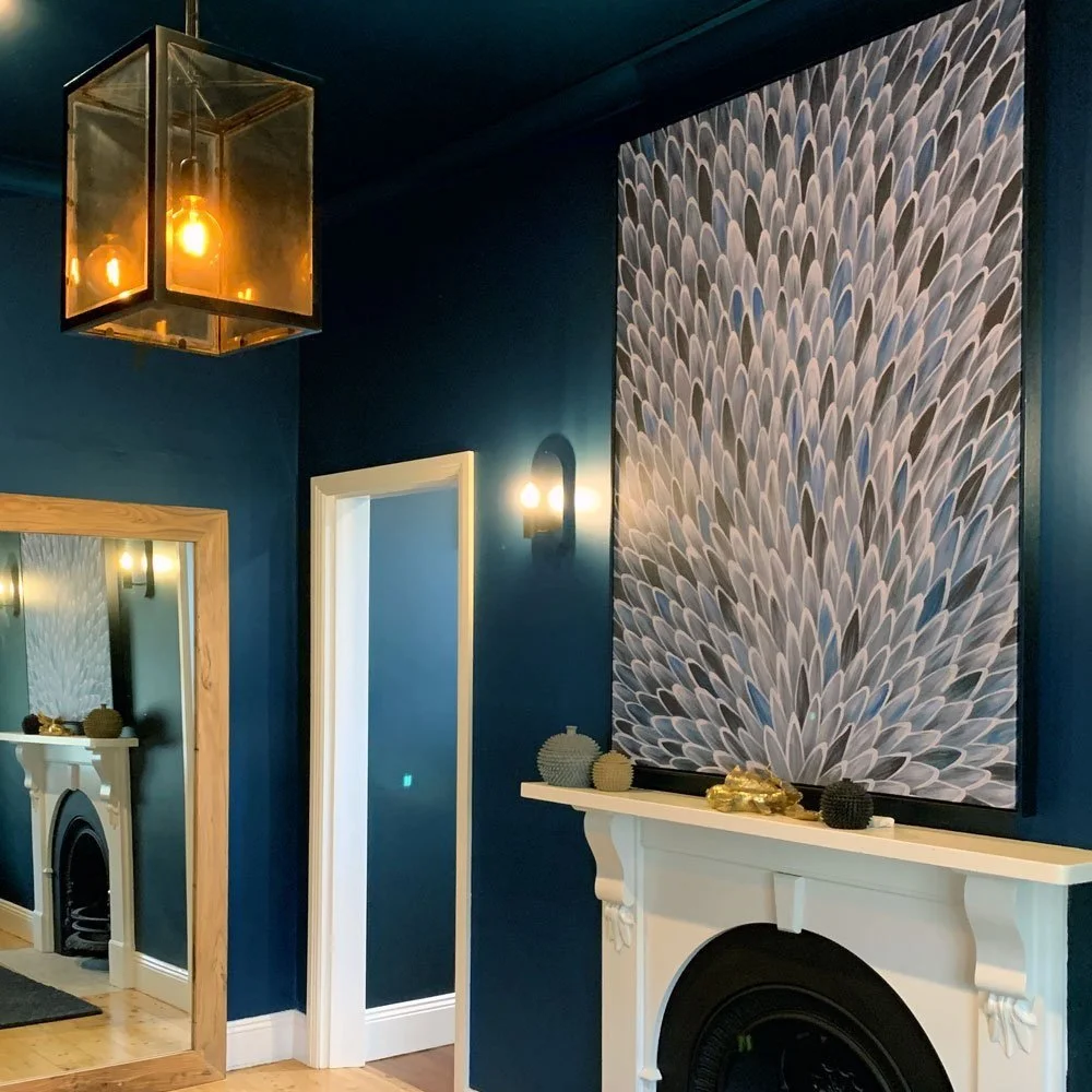 Dark blue walls and ceiling with a large art canvas over the fireplace