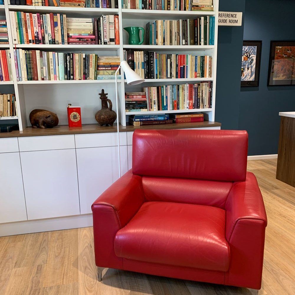 Library area with custom h=joinery and a red leather chair designed by Hue and Space