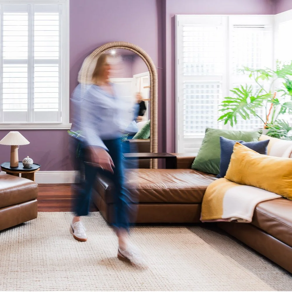 Blurred inage of an interior designer walking across a rug in a living room with mauve walls