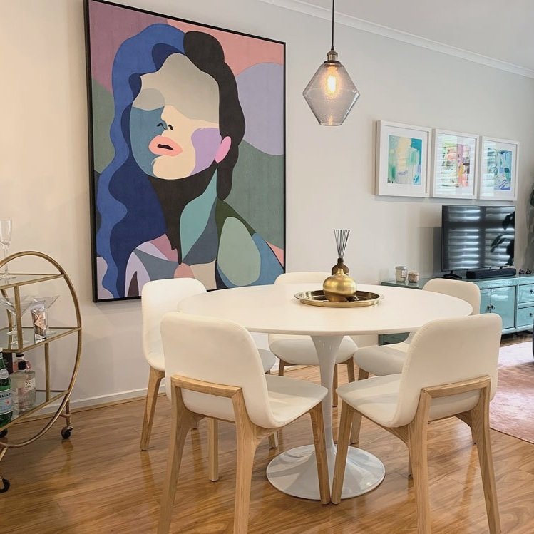 Grey glass pendant light over white dining table and colourful art in a dining room designed by Hue and Space Interior Design